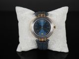 une photo d'une montre bleue posée sur un oreiller blanc