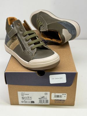 une paire de chaussures pour garçon dans une boîte posée sur une surface blanche