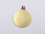 a close up of a gold disc pendant on a white background