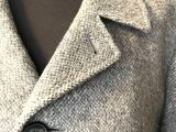 Ce manteau est en laine et comporte un bouton sur le devant.
