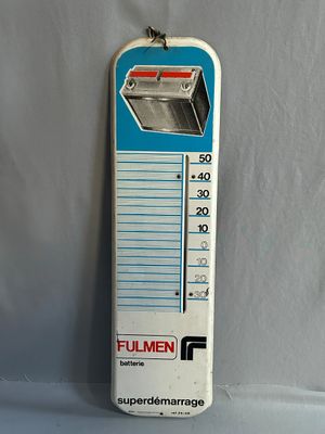 un thermomètre accroché à un mur blanc, sur un fond bleu et blanc