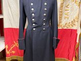 une photo d'un manteau militaire posé sur un mannequin devant un drapeau