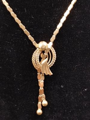 a gold necklace with a bird on it on a mannequin