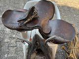 a horse saddle and a pair of shoes on the ground