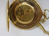 a gold pocket watch with a chain hanging from it ' s side