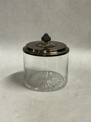a glass jar with a silver lid and a pine on top