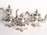three silver teapots sitting on a white surface