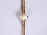 an image of a gold wrist watch with a chain around it