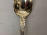 a silver spoon with a handle on a white surface