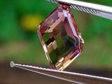 un diamant rose et vert tenu par une pince
