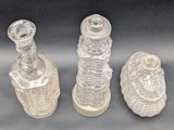 three clear glass bottles sitting next to each other on a table