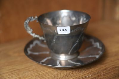 une tasse et une soucoupe en argent posées sur une table en bois