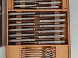 several forks and spoons in a wooden box with a brown case