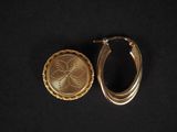 un gros plan sur une paire de boucles d'oreilles en or posées sur une surface noire