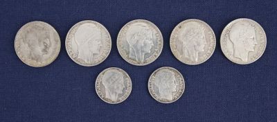 six different types of silver coins on a blue surface