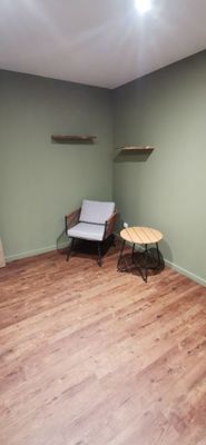 une pièce avec un canapé, un fauteuil et des étagères fixées au mur
