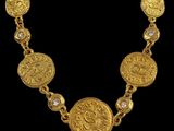 a close up of a gold necklace on a black background