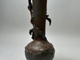 a bronze vase on a wooden stand on a white background