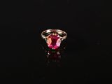 une bague en tourmaline rose et diamants posée sur un fond noir