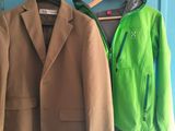 two jackets hanging on a coat rack in front of a blue door