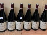six bottles of wine are lined up on a wooden table