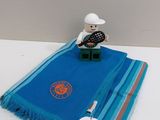 un ours en peluche assis sur une table, recouvert d'une couverture bleue