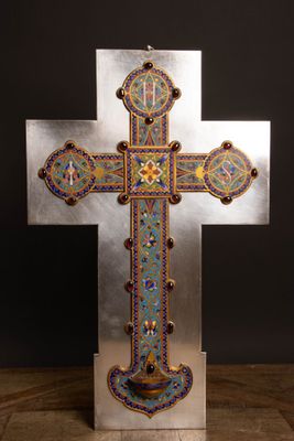 une croix en argent ornée de motifs multicolores, posée sur une table