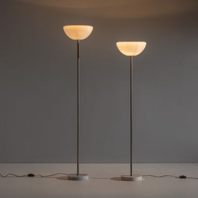 Deux lampes sont posées sur une table devant un mur gris.
