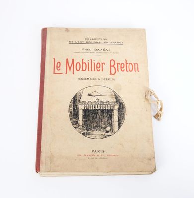 un vieux livre posé sur une table à côté d'un mur blanc