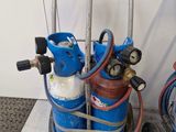 un chariot avec des bouteilles de gaz et des tuyaux posé par terre