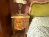 un lit avec une tête de lit verte et une table de chevet sur laquelle est posée une lampe
