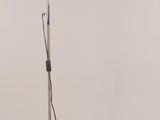 Le lampadaire est doté d'un pied en métal et d'une base blanche.