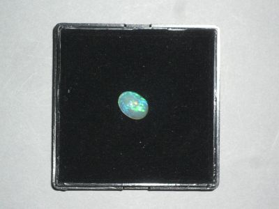 une pierre d'oplite dans une boîte noire posée sur une surface blanche