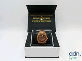 une image représentant une montre en bois dans un coffret, posée sur une surface blanche