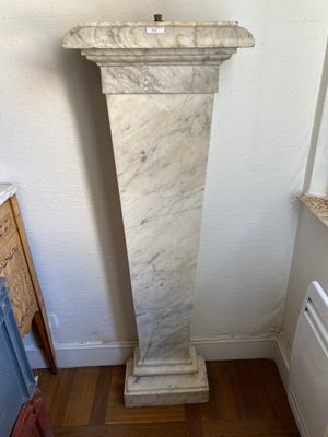 a tall marble pedestal in the corner of a room