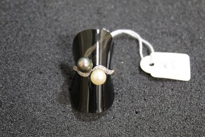 a ring with two pearls on it sitting on a table