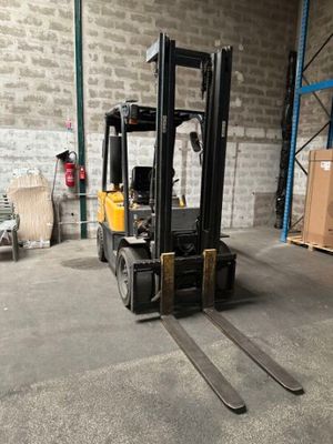 un chariot élévateur dans un entrepôt, avec des cartons et des palettes en arrière-plan