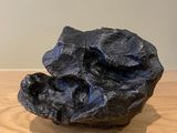 a close up of a black rock on a wooden table