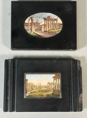 two small black boxes with paintings on them sitting on a white surface