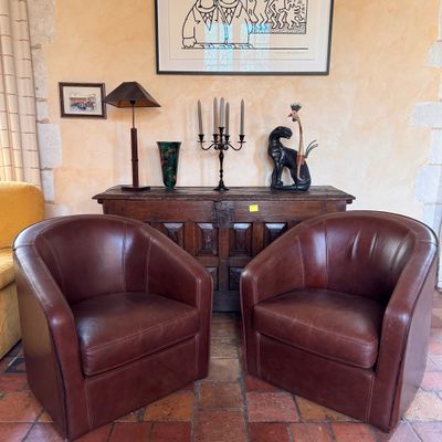 two brown leather chairs sitting next to each other in a living room