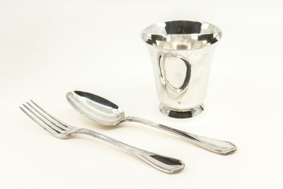deux cuillères et une fourchette à côté d'une tasse en argent