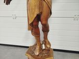 a wooden statue of a man holding a knife and fork