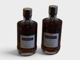 deux bouteilles de whisky posées côte à côte sur une surface blanche