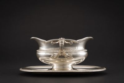 une assiette en argent posée sur une soucoupe, le tout sur fond noir