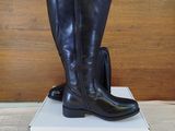 pair of black boots sitting on top of a box on a bed