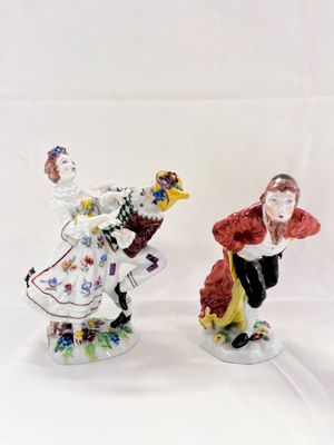 two figurines of a man and a woman dressed in costumes