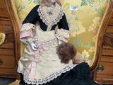 a doll that is sitting on a chair with a teddy bear