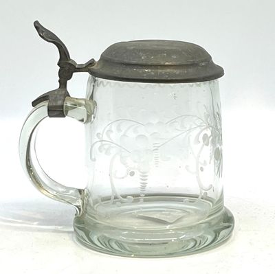 un mug en verre avec une anse posé sur une surface blanche