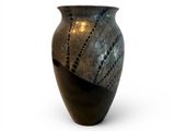 a black and silver vase sitting on a white surface