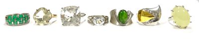 six different rings with green and yellow stones in them on a white surface